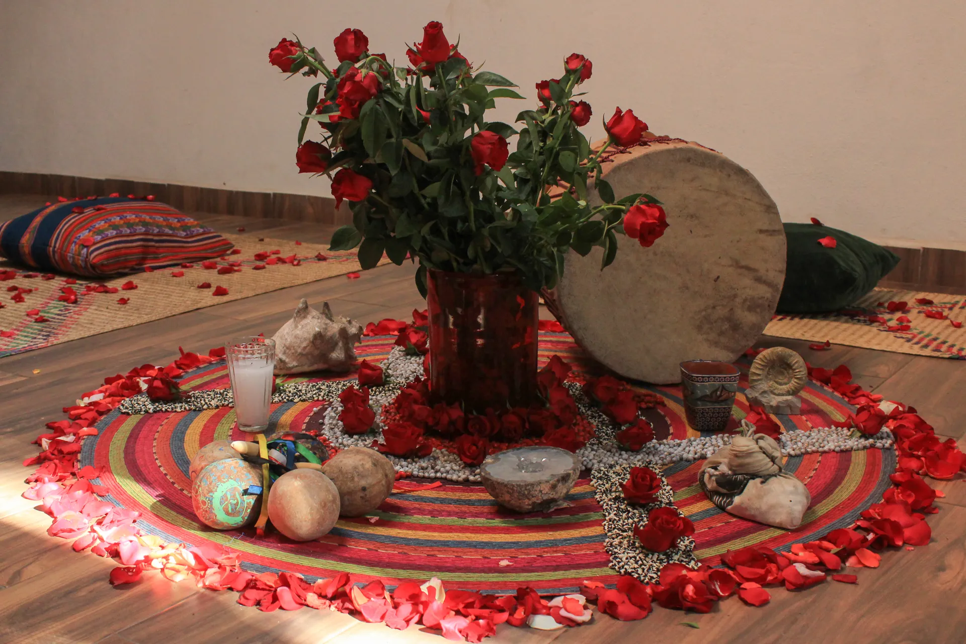 Círculo de pétalos de rosa con tambor, caracoles y ofrendas