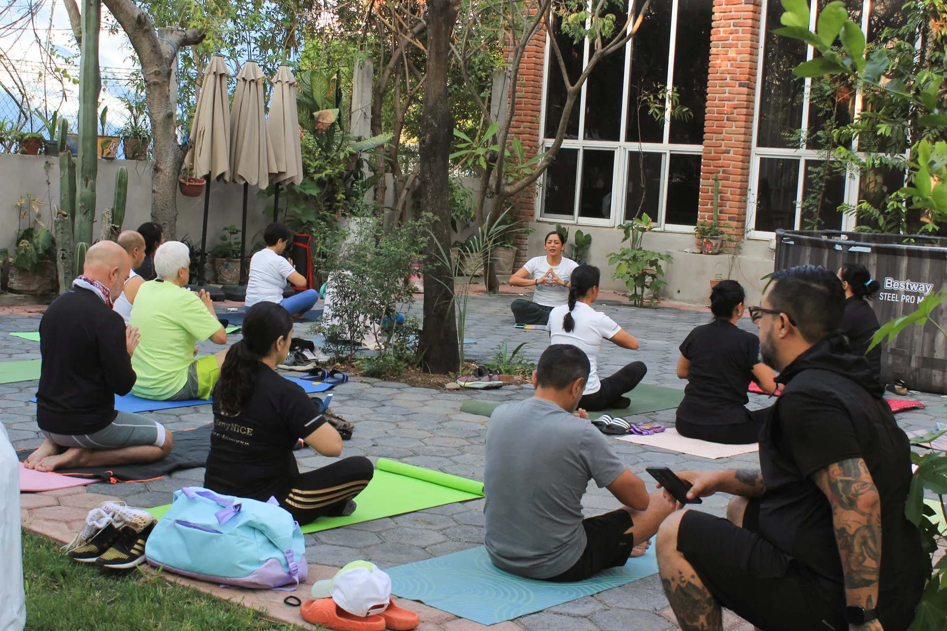 Clase de yoga en el jardín, bajo los árboles