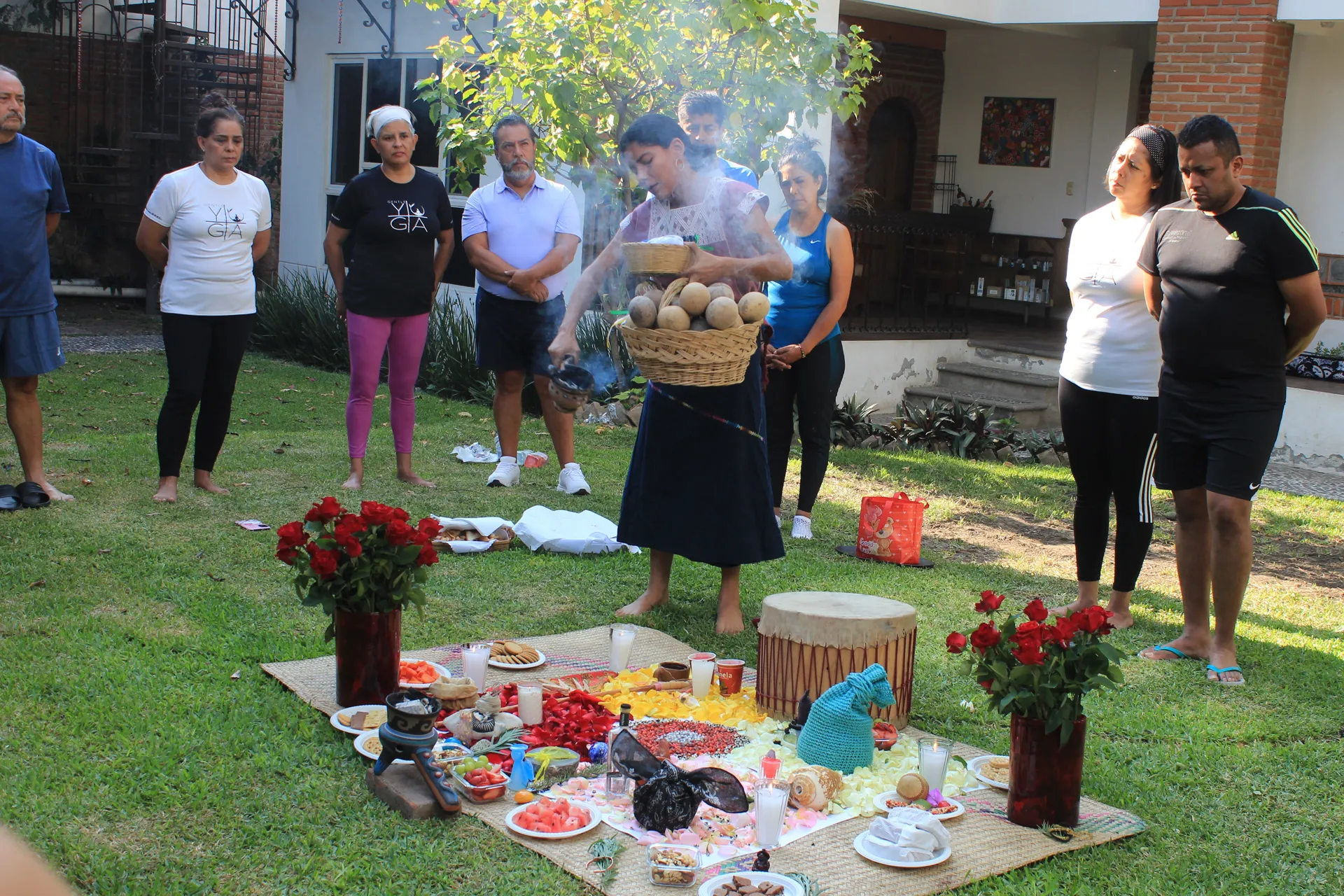 Ceremonia grupal en el jardín frente al altar con rosas y tambor