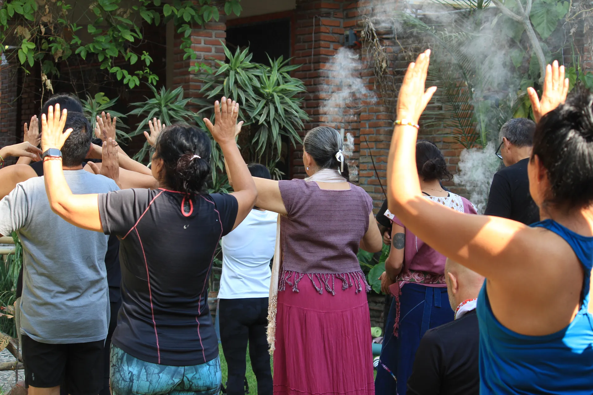 Grupo alza los brazos entre el humo de copal