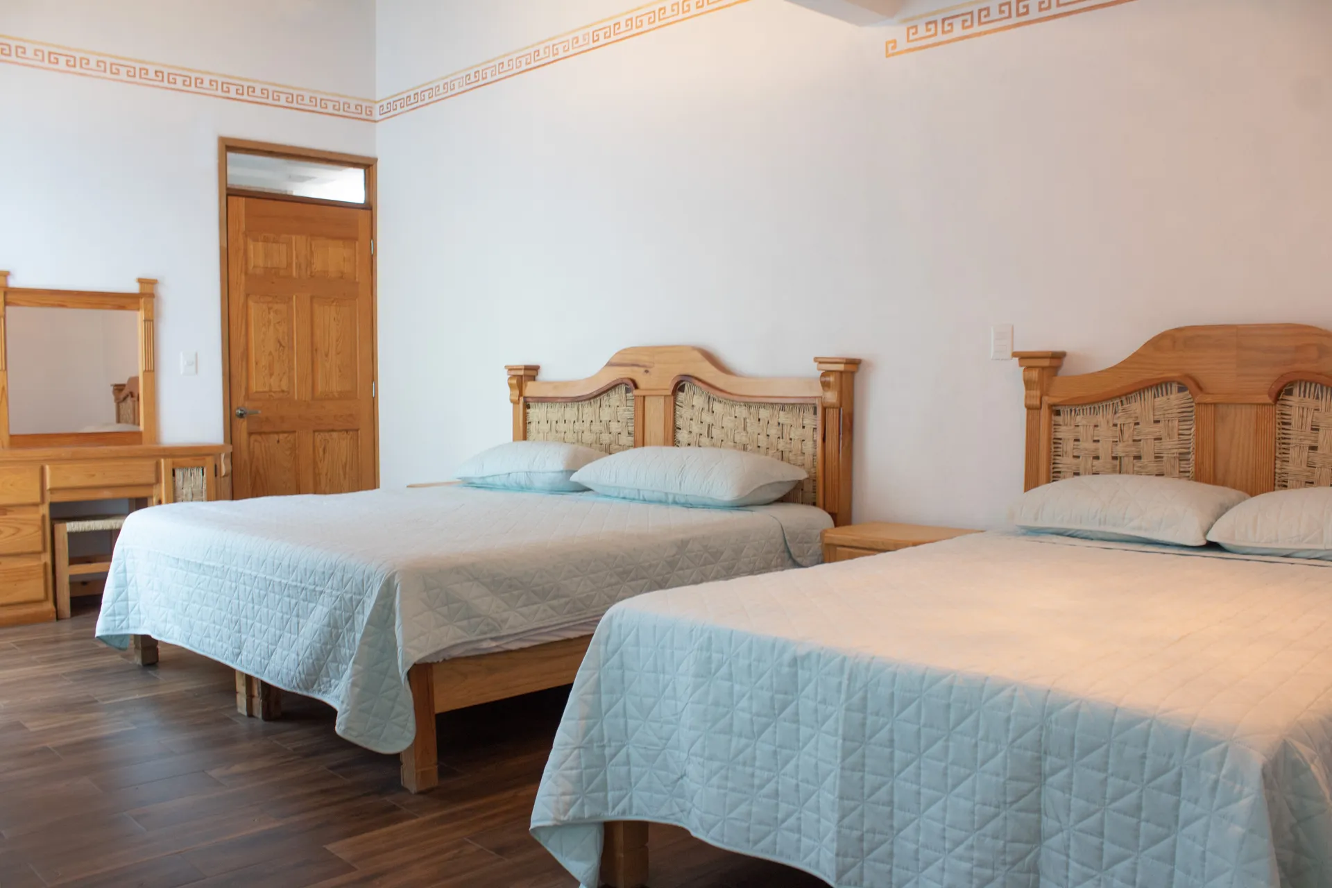 Habitación con dos camas, tocador y puerta de madera