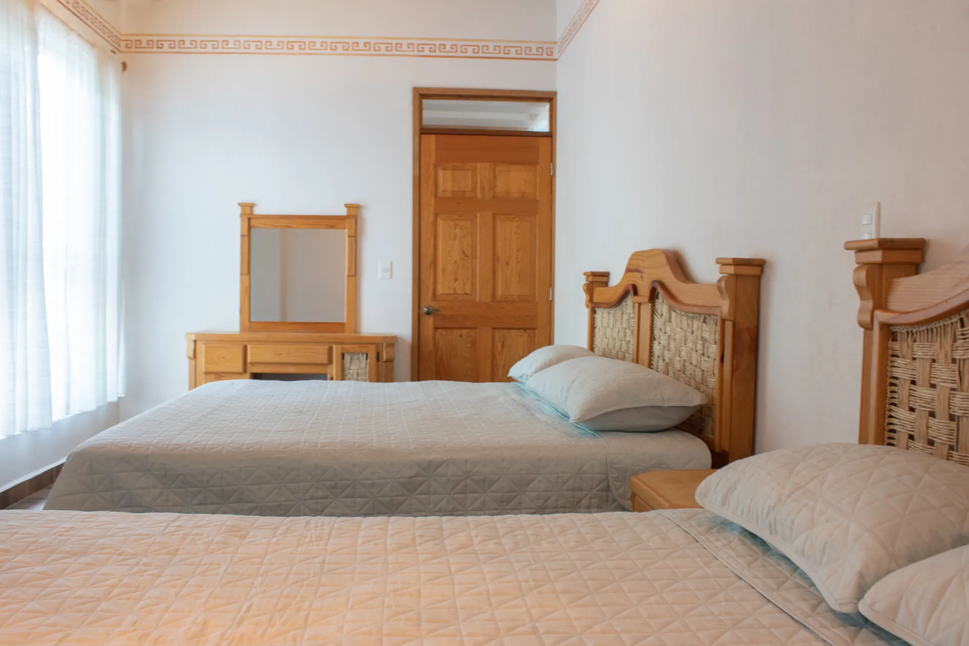 Habitación con dos camas, tocador y puerta de madera