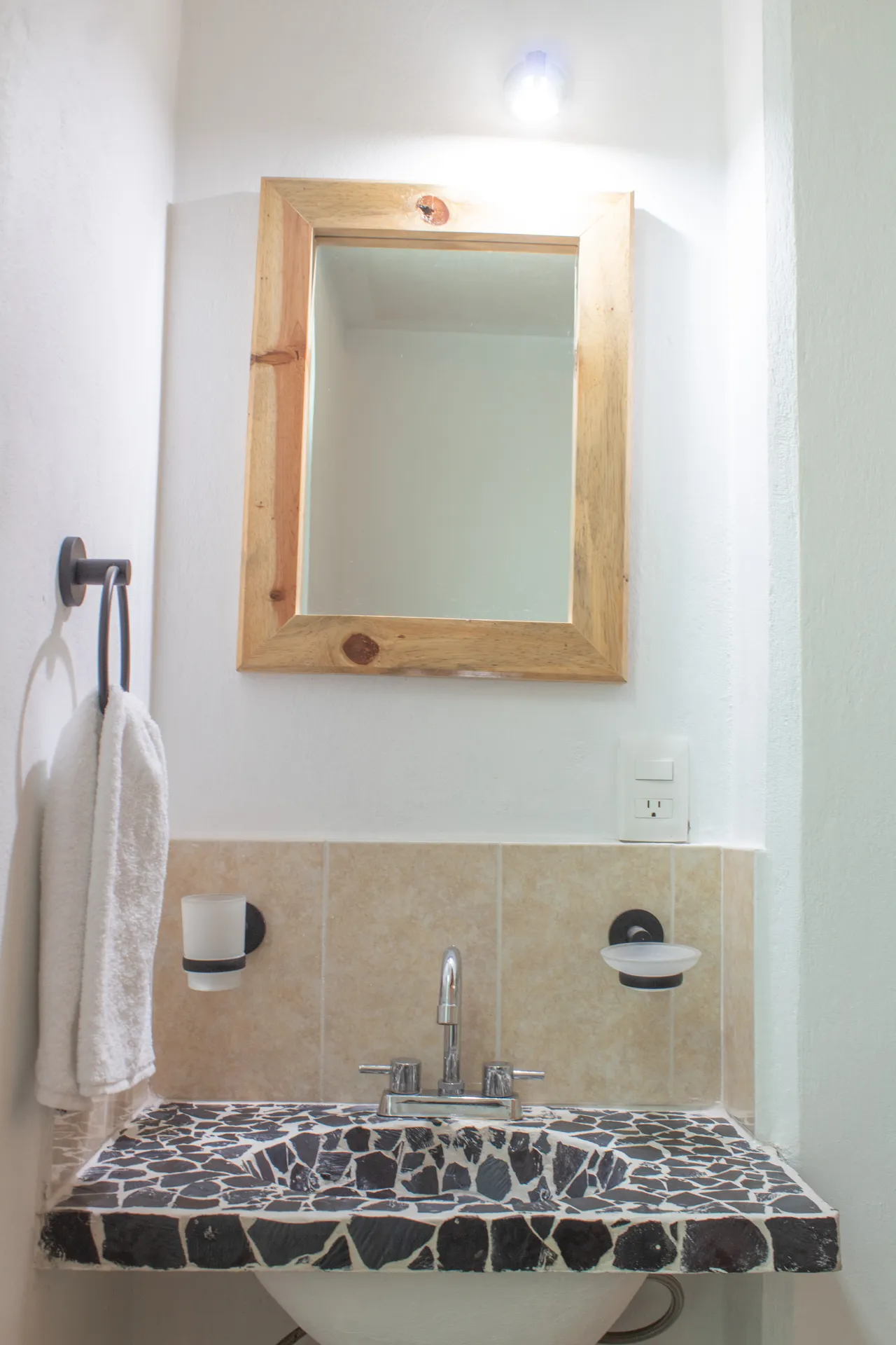 Baño con lavabo de piedra y espejo con marco de madera