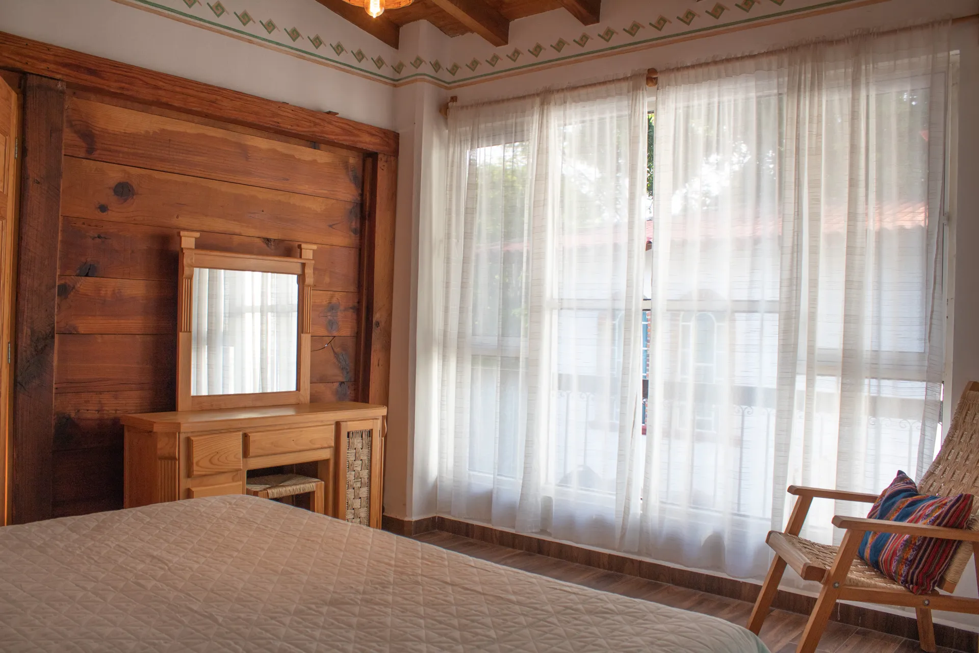 Habitación con pared de madera, ventanal y cama matrimonial