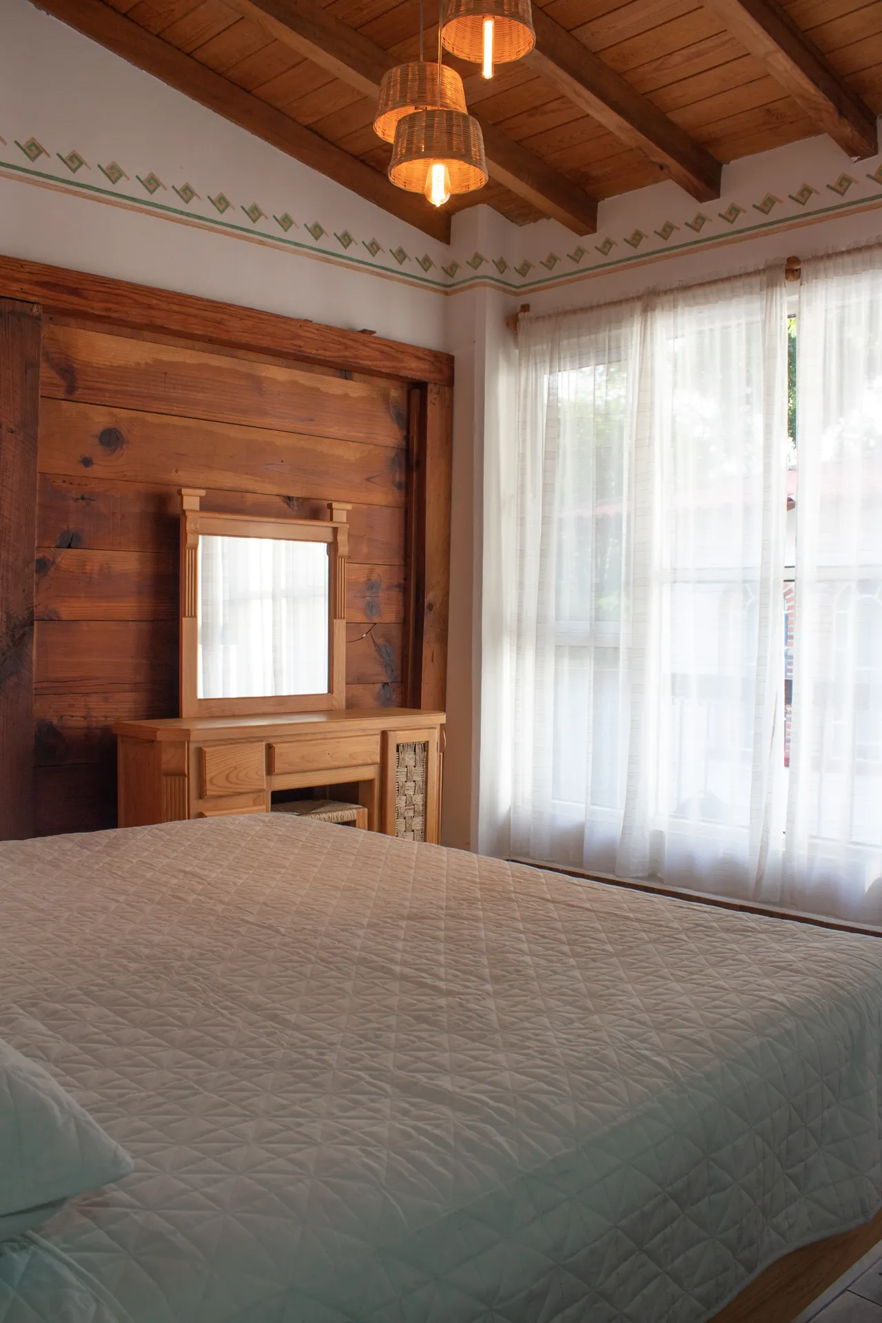 Habitación con pared de madera, ventanal y cama matrimonial