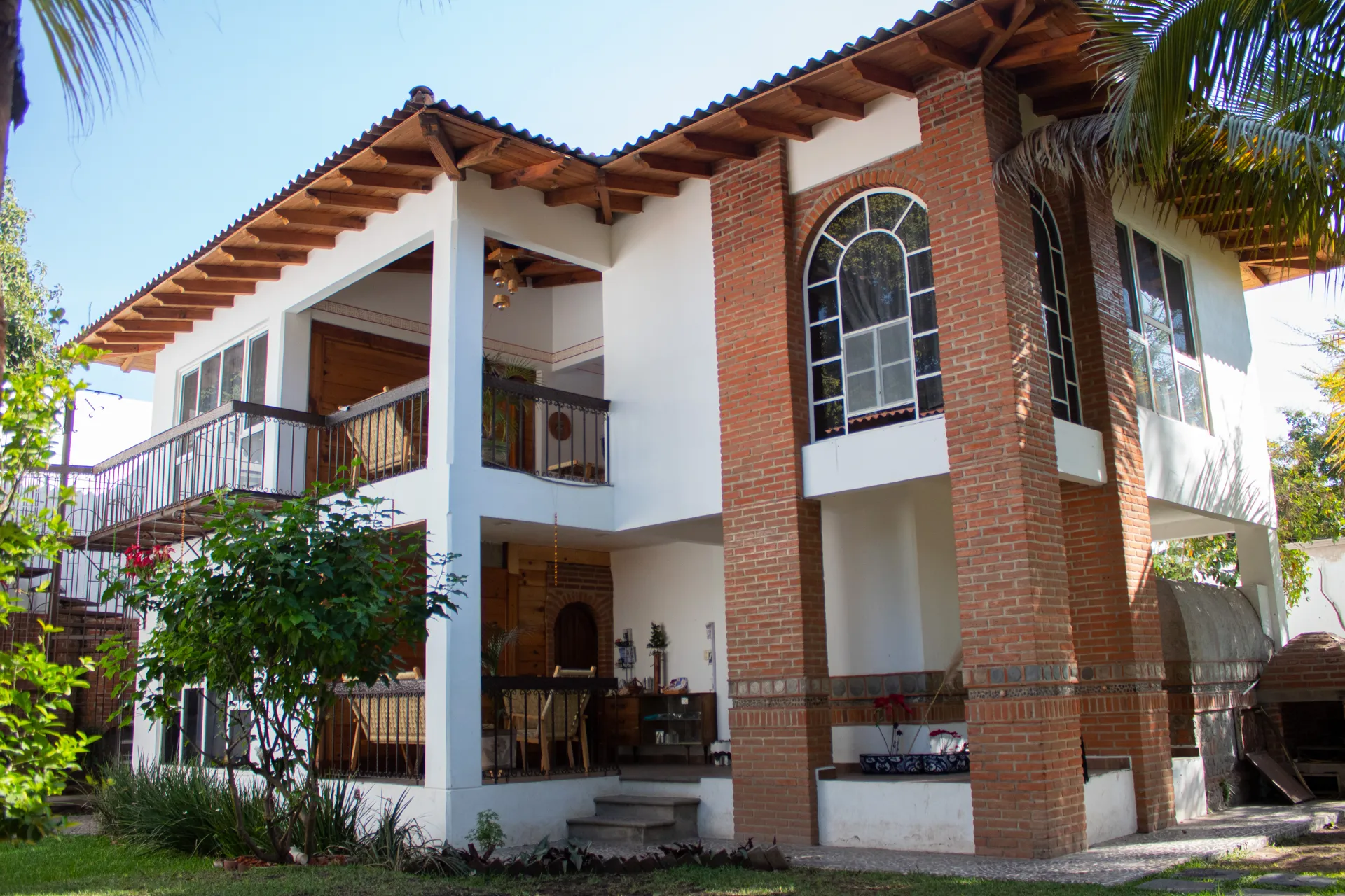 Fachada de la casa de huéspedes: dos pisos, teja, ladrillo y jardín