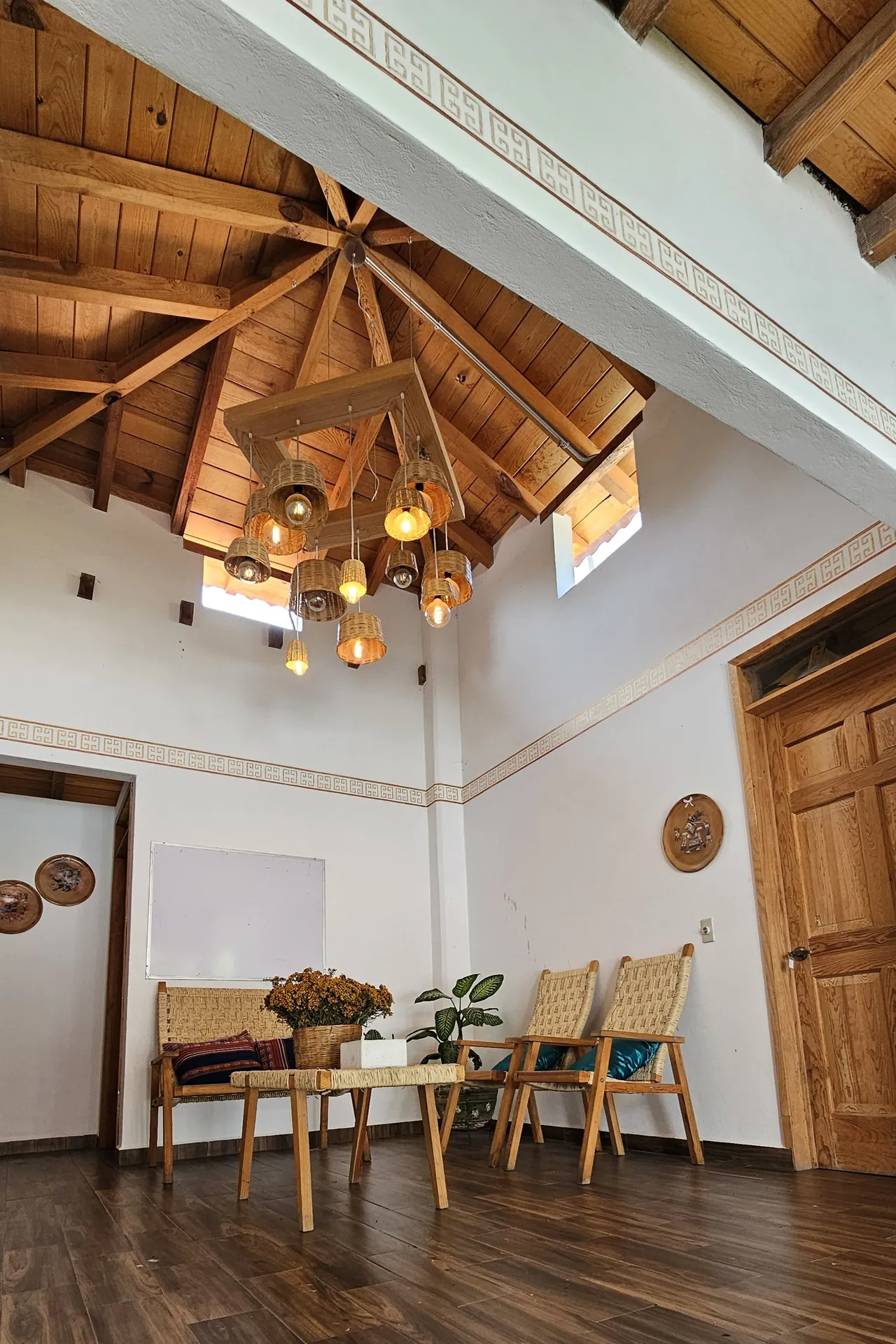 Estancia de techo alto con vigas de madera en estrella y candil de palma