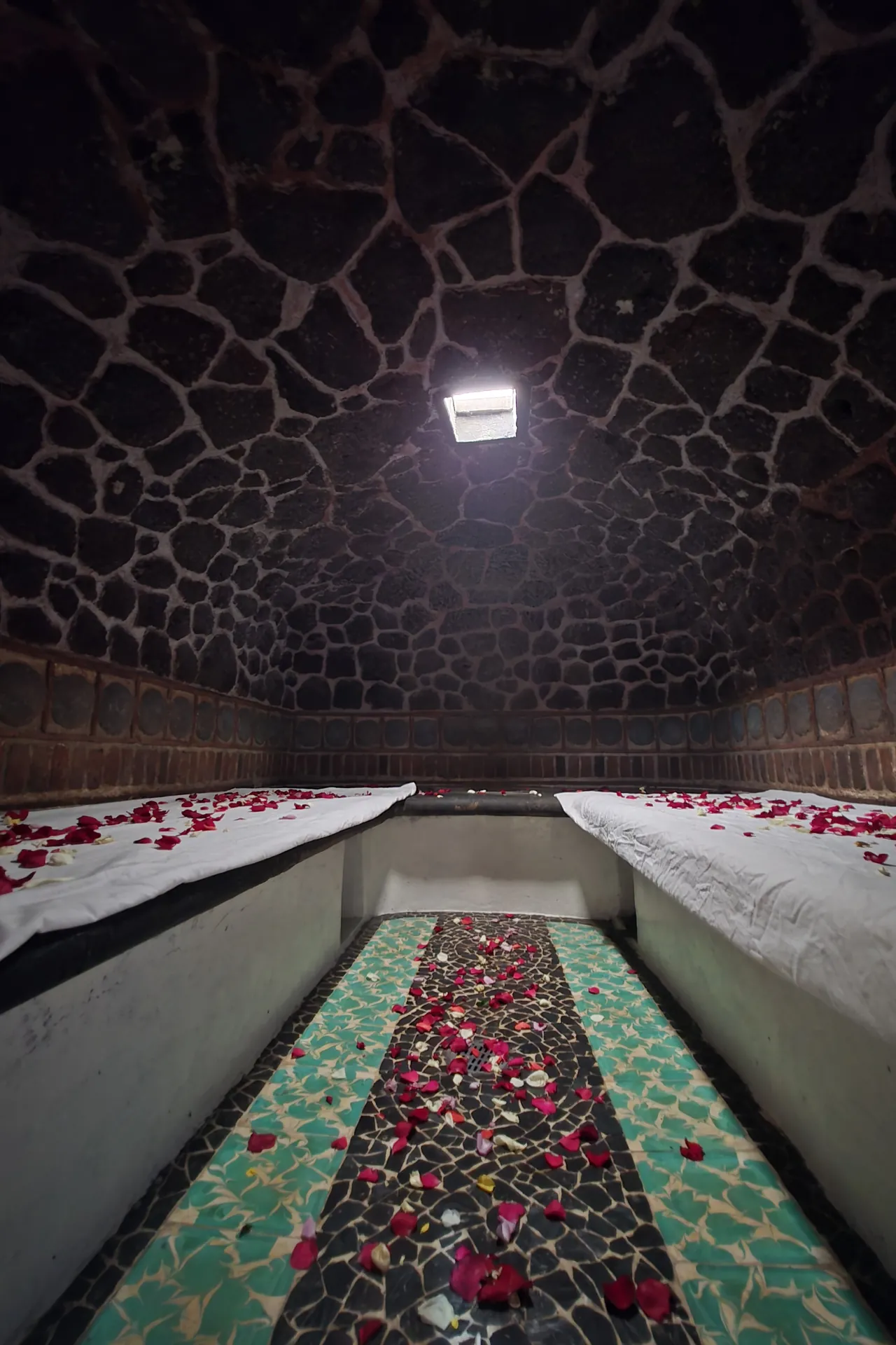Interior del temazcal: bóveda de piedra, bancas con pétalos y camino de mosaico