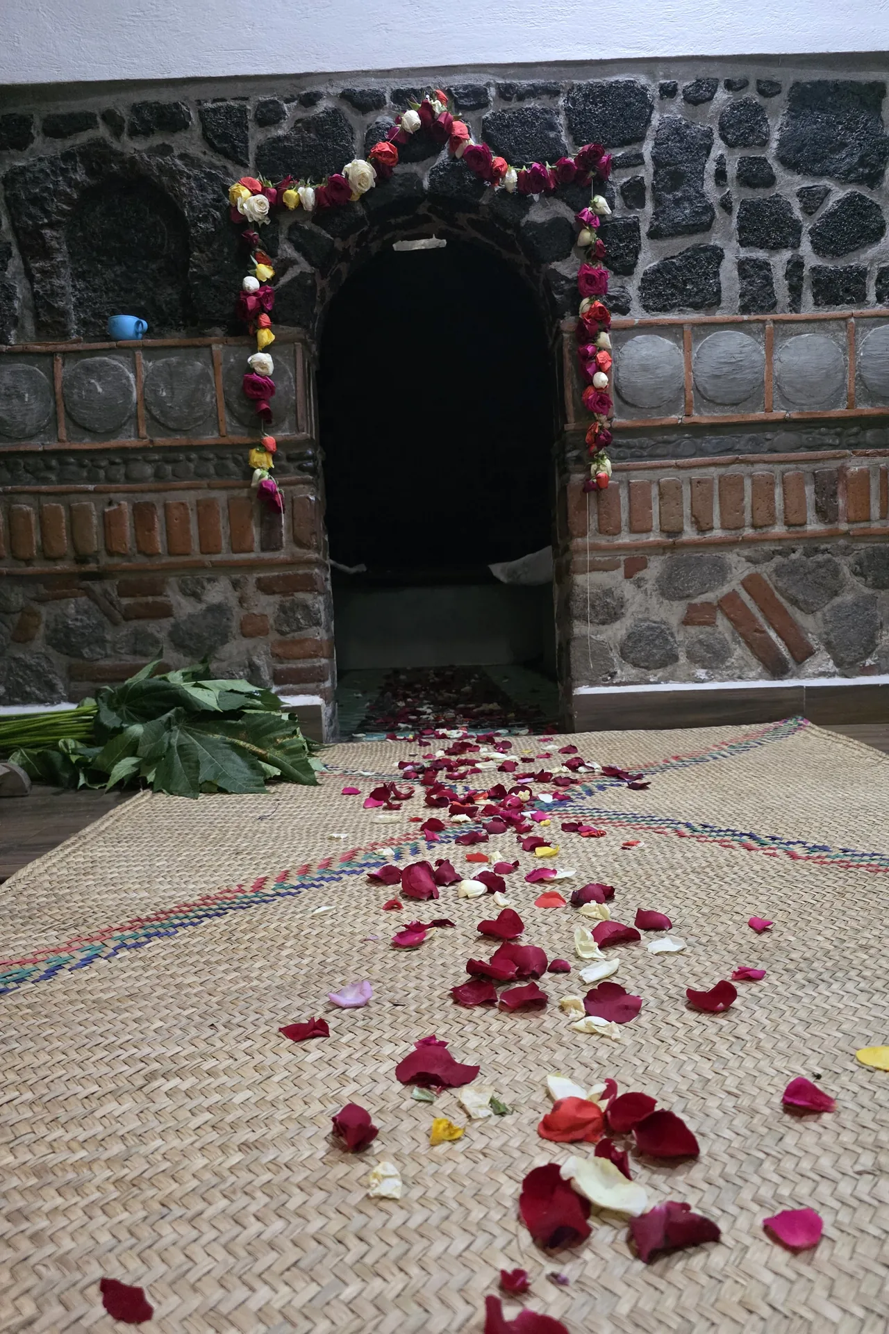 Entrada del temazcal con arco de rosas y camino de pétalos