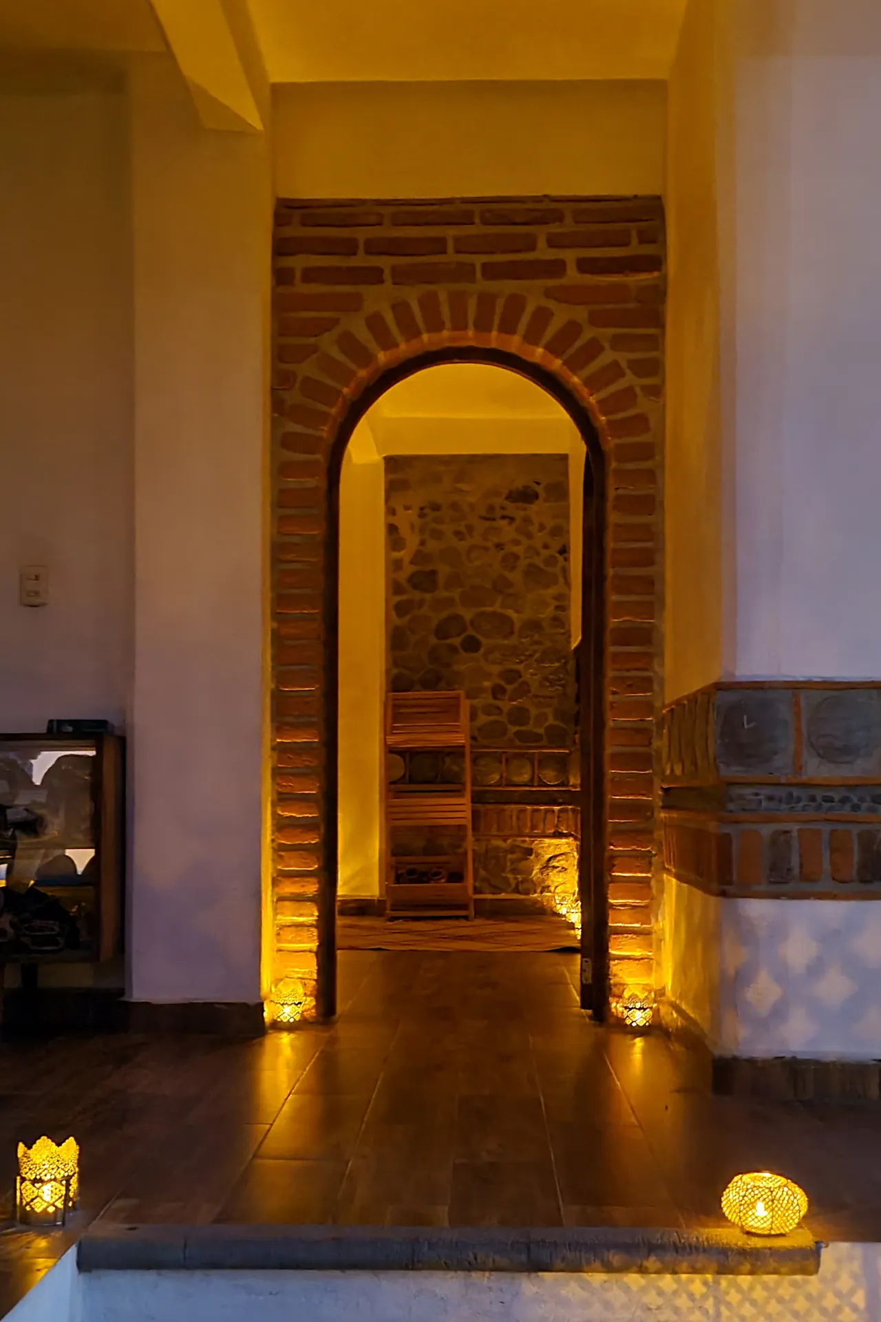 Puerta en arco de ladrillo iluminada con velas en la entrada al temazcal